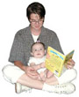 Mother with young daughter sitting on her lap. Mother is reading to the baby.